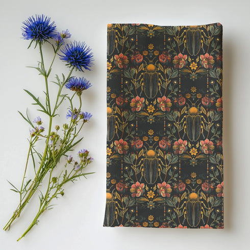 Set of four dark green cloth napkins with a repeating pattern of golden beetles, coral flowers, and ochre wildflowers in an intricate botanical and entomological design.